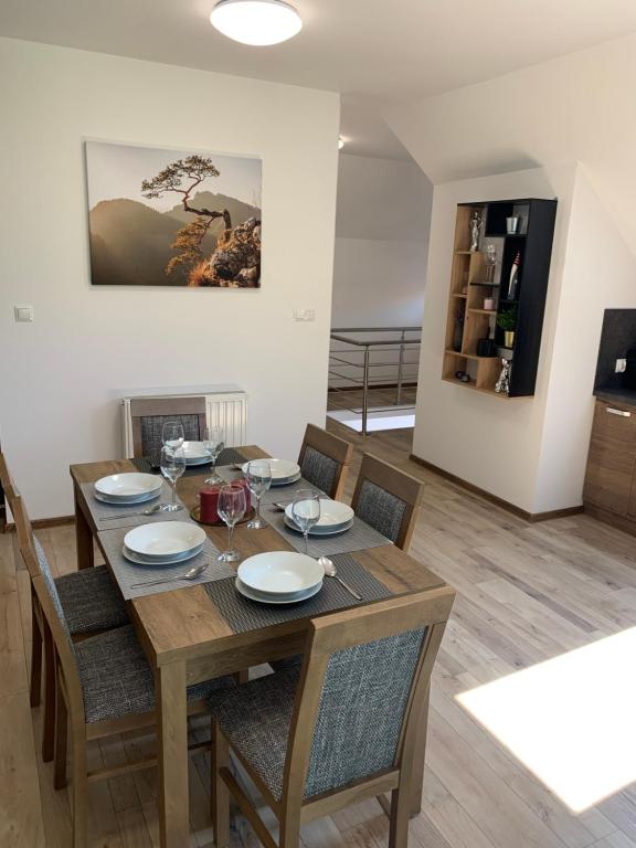 uma sala de jantar com uma mesa de madeira e cadeiras em Cozy 2-bedroom vacation apartment with entire top floor em Gaj