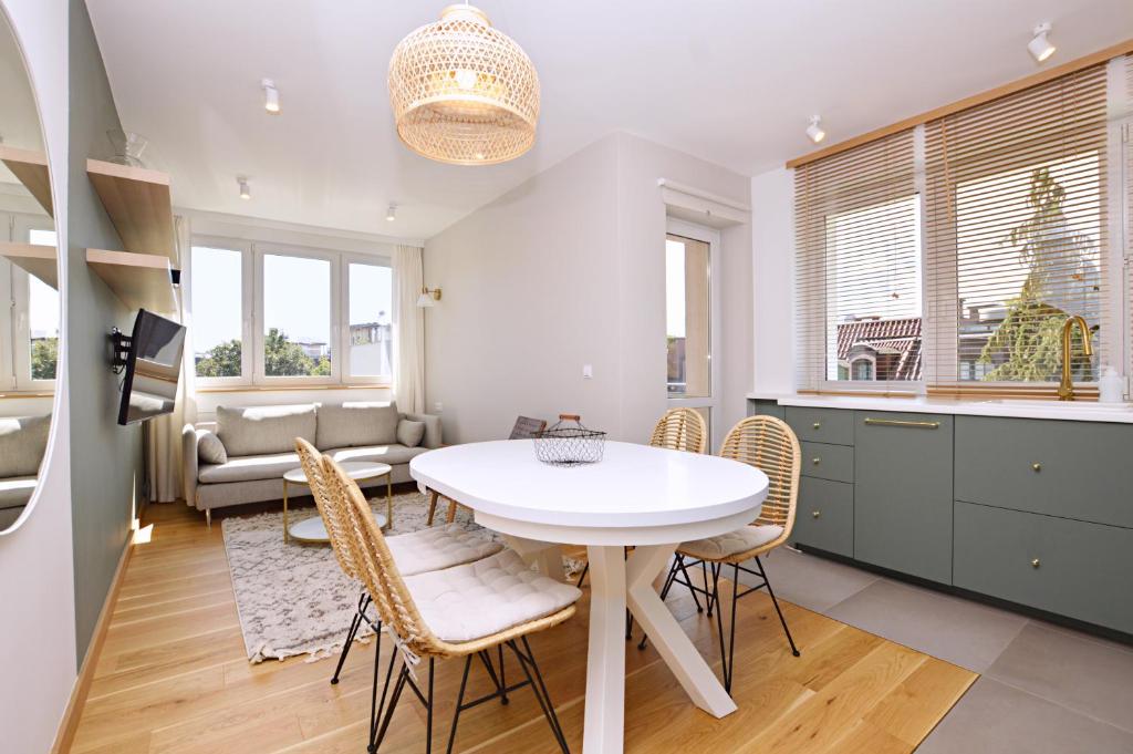 eine Küche und ein Esszimmer mit einem weißen Tisch und Stühlen in der Unterkunft Victus Apartamenty, Apartament Boho in Sopot