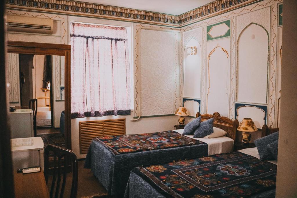 a bedroom with two beds and a large window at Minzifa Inn in Bukhara