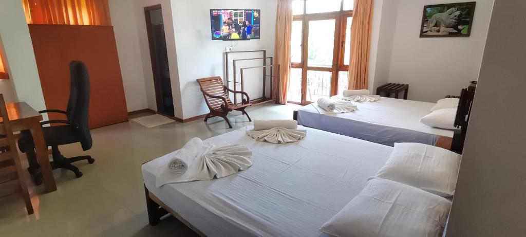 a room with three beds and a table and chairs at Rajarata Lodge in Anuradhapura