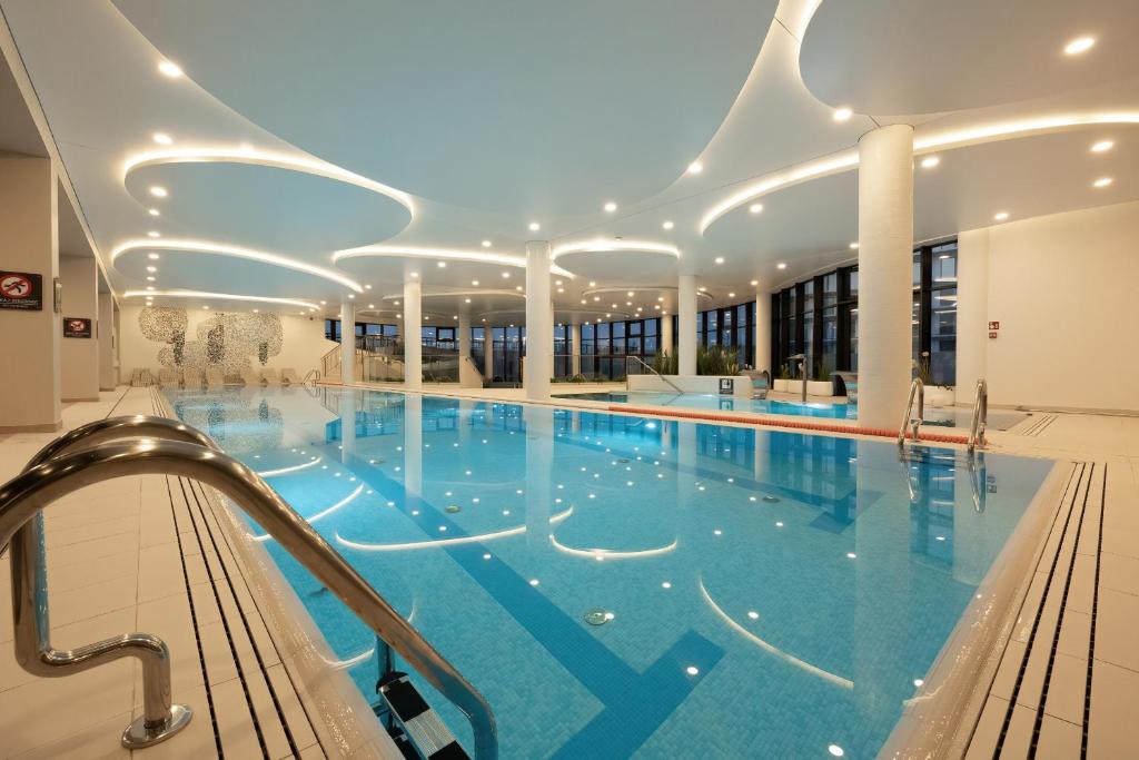 una grande piscina con acqua blu in un edificio di Apartment Polanki Aqua Kołobrzeg by Renters Prestige a Kołobrzeg