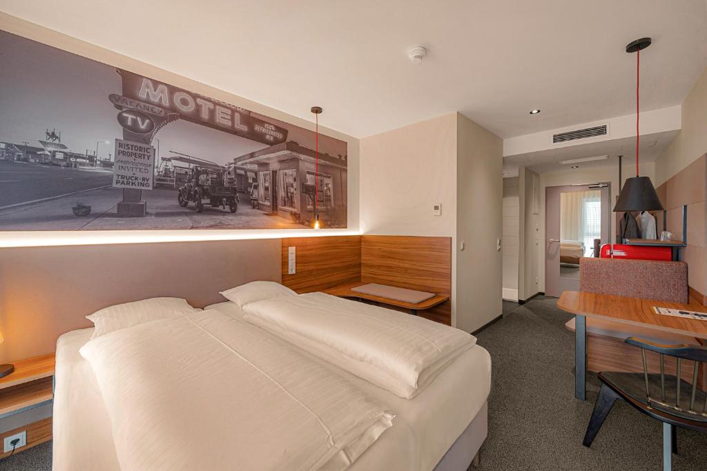 a bedroom with a large white bed and a desk at Zündwerk - Motel in Strasshof an der Nordbahn