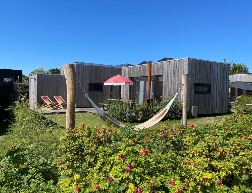 a hammock in a garden in front of a building at WAD NOU Terschelling heerlijk duurzaam chalet! in Midsland