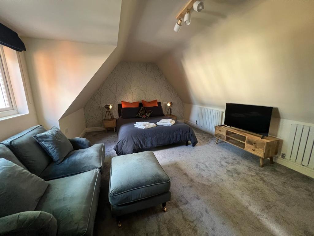 a attic bedroom with a bed and a couch at The Annexe, Farnborough in Farnborough