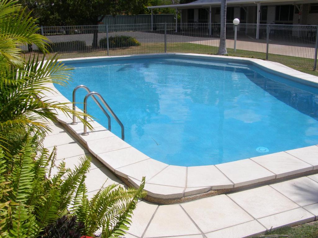 ein großer Pool mit einer gefliesten Terrasse um ihn herum in der Unterkunft Gayndah A Motel in Gayndah