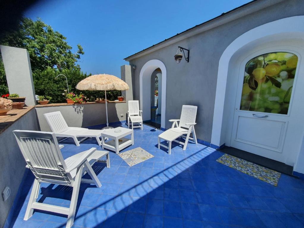 a patio with white chairs and an umbrella at Casa Rossella in Procida