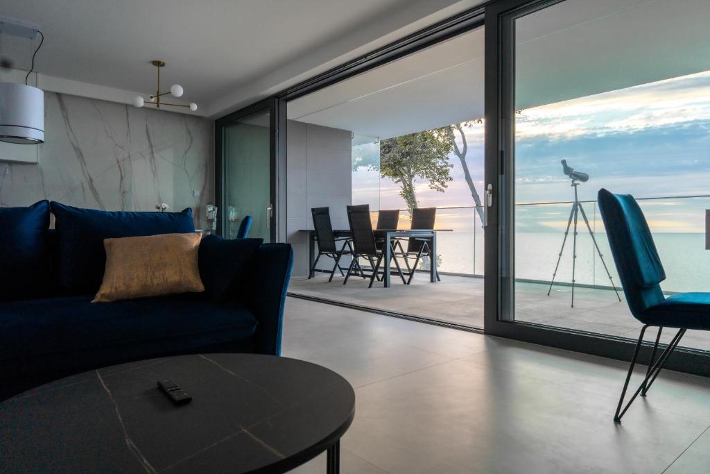 een woonkamer met een blauwe bank en uitzicht op de oceaan bij HORIZON HEVENIA Rewal Apartament z dużym tarasem i widokiem na morze in Rewal