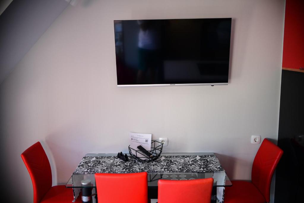 a table with red chairs and a television on a wall at Medius Park Apartment in Sandanski