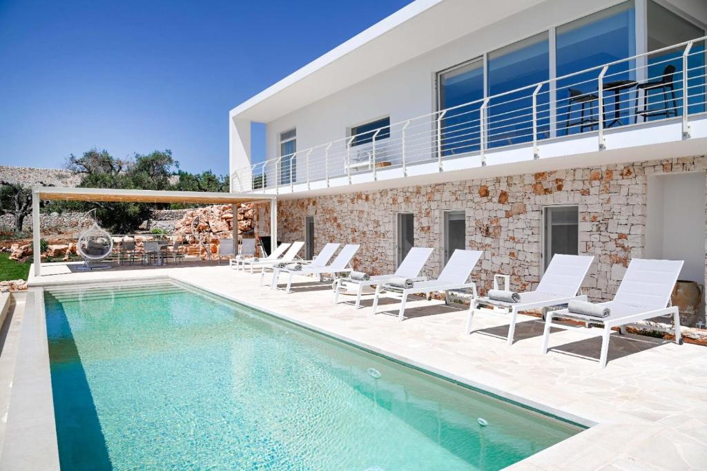 une villa avec piscine et chaises longues dans l'établissement Villa Panitria, à Ostuni