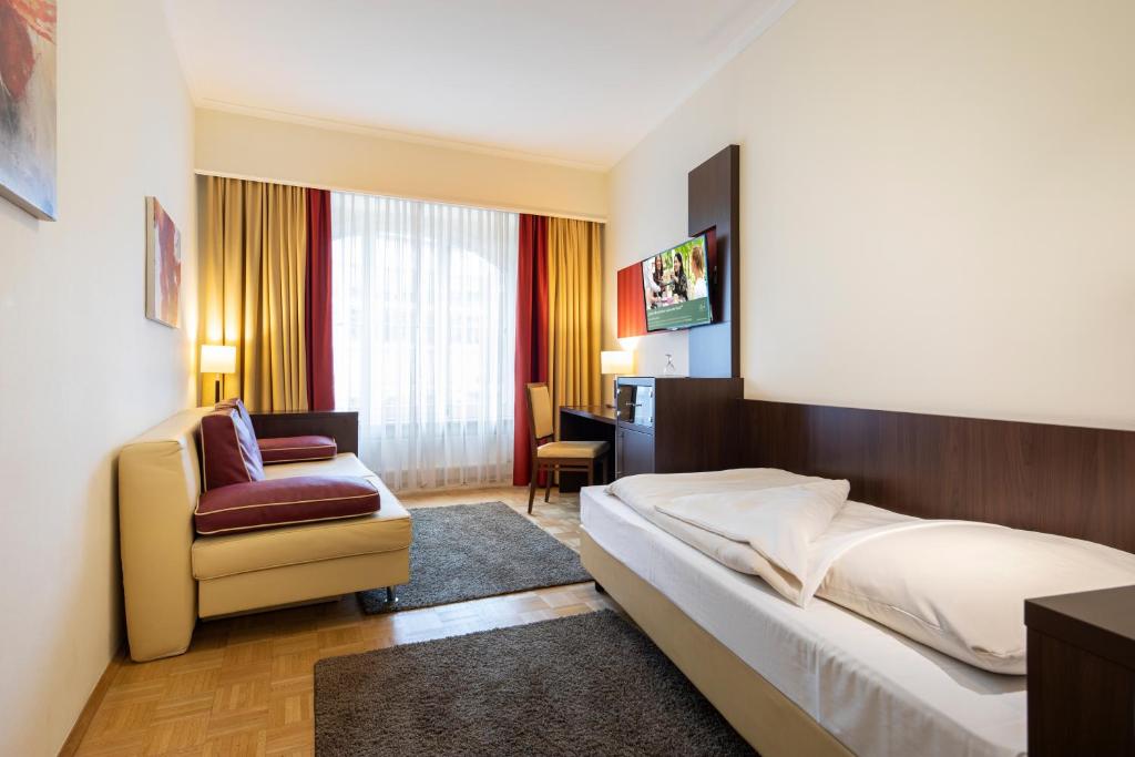 a hotel room with a bed and a chair at ACHAT Sternhotel Bonn in Bonn