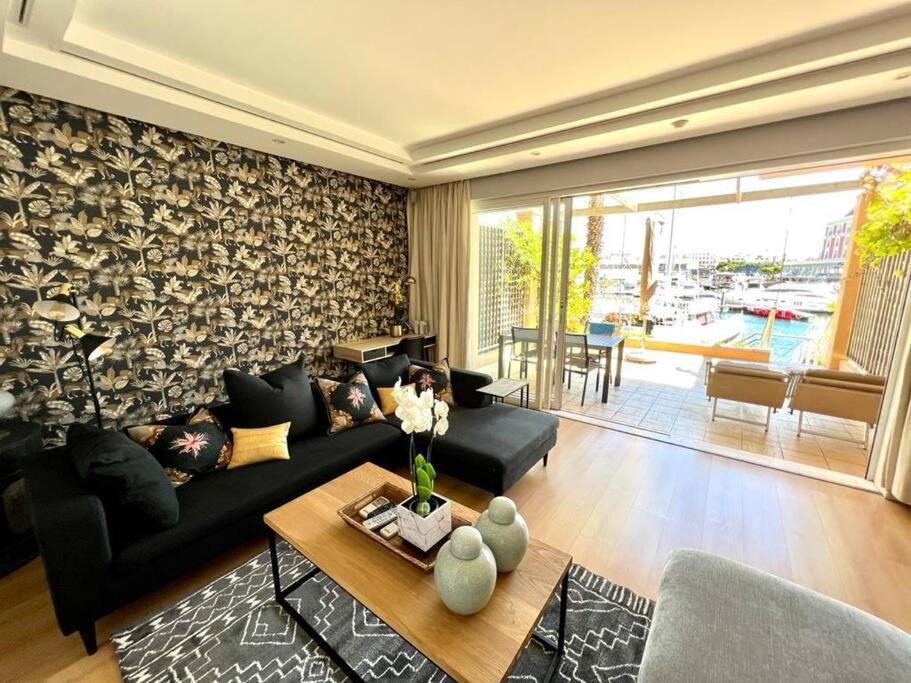 sala de estar con sofá negro y mesa en Parama 003 Secure, Luxurious Waterfront Apartment en Ciudad del Cabo