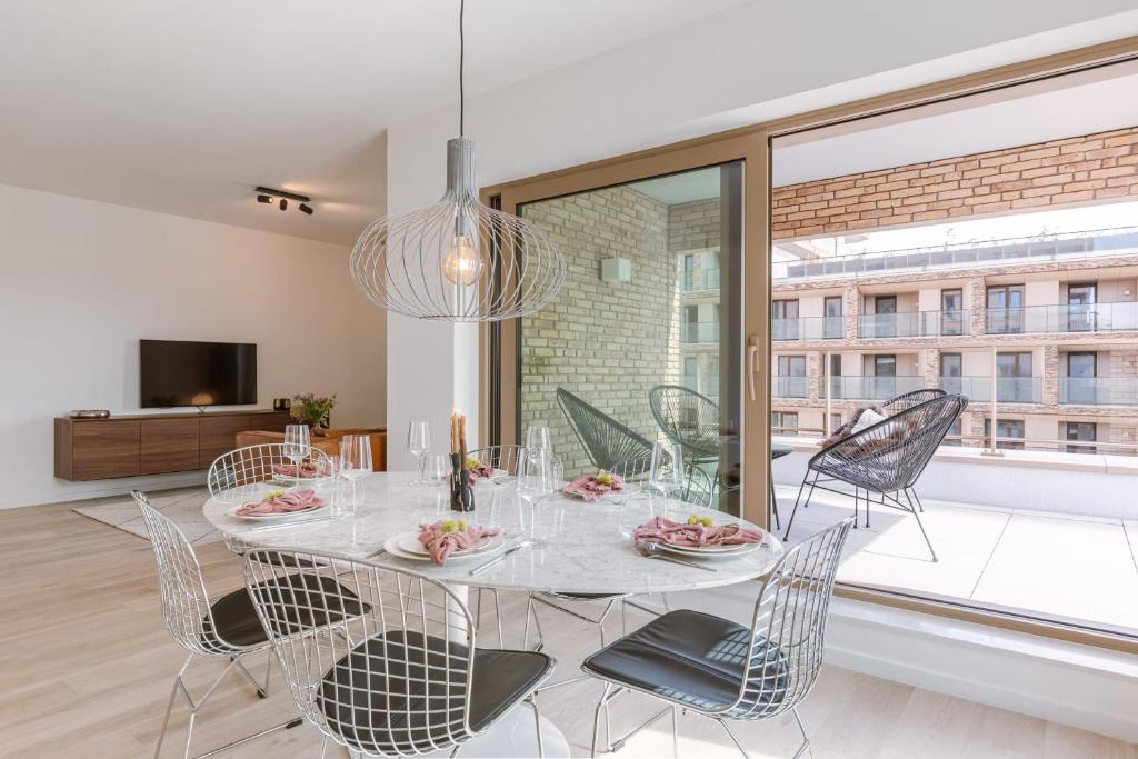 uma sala de jantar com mesa e cadeiras e uma grande janela em Beautifully decorated apartment with sunny terrace em Oostende