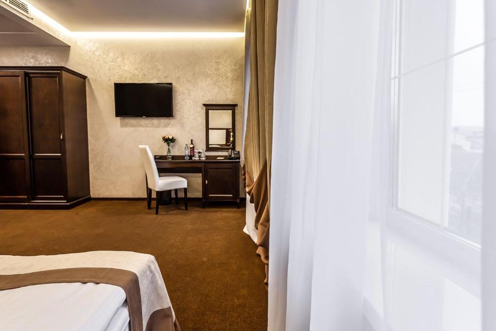 a hotel room with a bed and a desk and a window at Optima Collection Khmelnytskyi in Khmelnytskyi