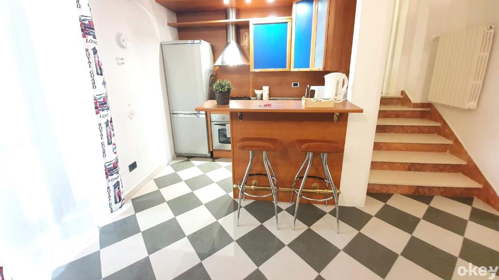 una cucina con pavimento a scacchi, bancone e sgabelli di House of Music - Bari Centro a Bari
