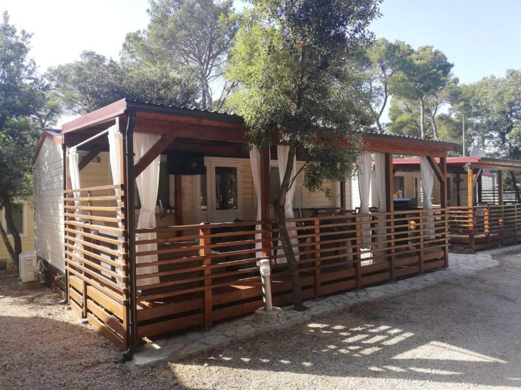 a wooden cabin with a tree in front of it at Mobile home Happy Summer in Biograd na Moru