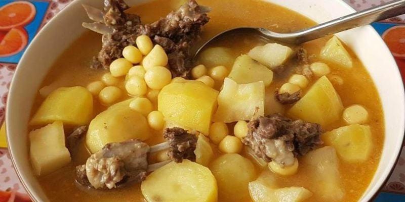 een kom soep met vlees en bonen en een lepel bij Pam de Terra 