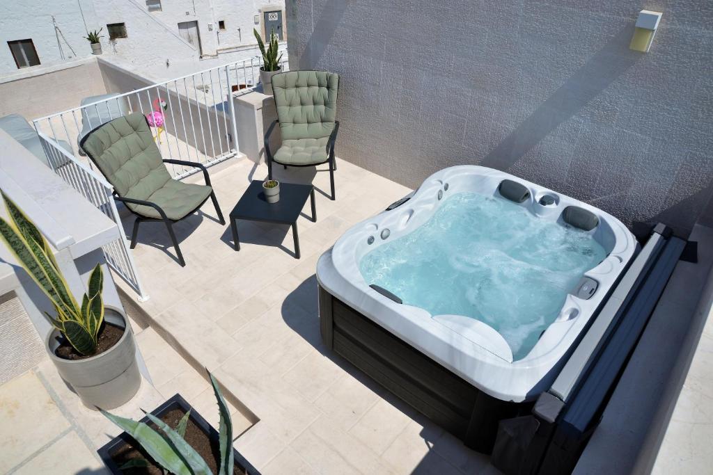 - Balcón con bañera de hidromasaje, sillas y mesa en Attico Cinquantasei, en Cisternino