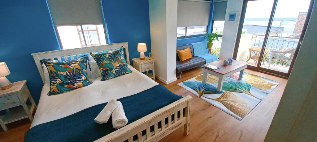 The Sandcastle Guesthouse - Melkbosstrand في مليكبوستراند: غرفة نوم بسرير كبير بجدار ازرق