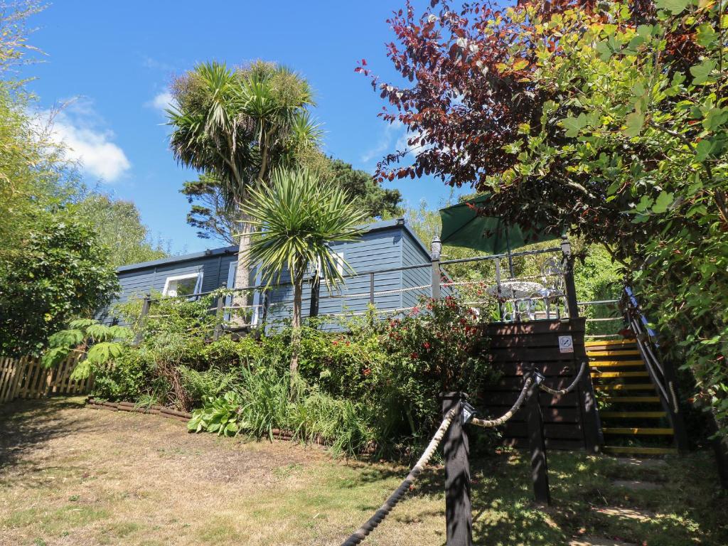 a house with stairs in a garden with trees at Palm Lodge in Penzance