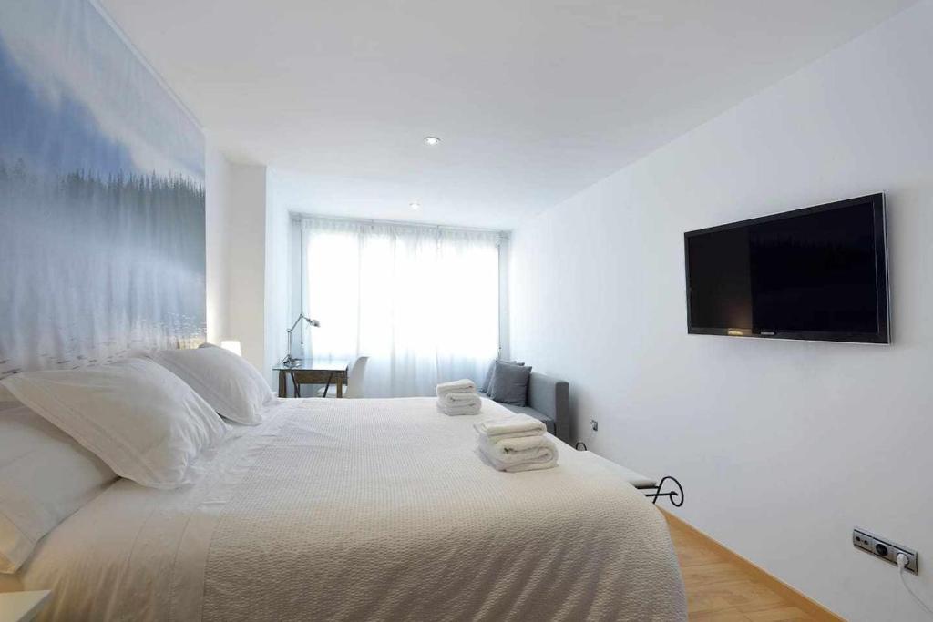 een witte slaapkamer met een groot bed en een flatscreen-tv bij Andrews house 60 m en el centro de Zaragoza in Zaragoza