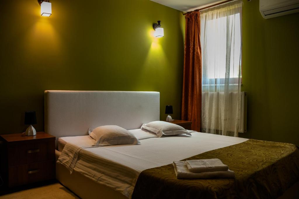 a bedroom with a bed with green walls and a window at Pensiunea Clasic Hunedoara in Peştişu Mare