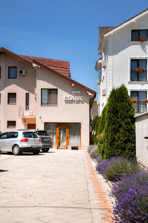 a building with cars parked in a parking lot at Pensiunea Clasic Hunedoara in Peştişu Mare