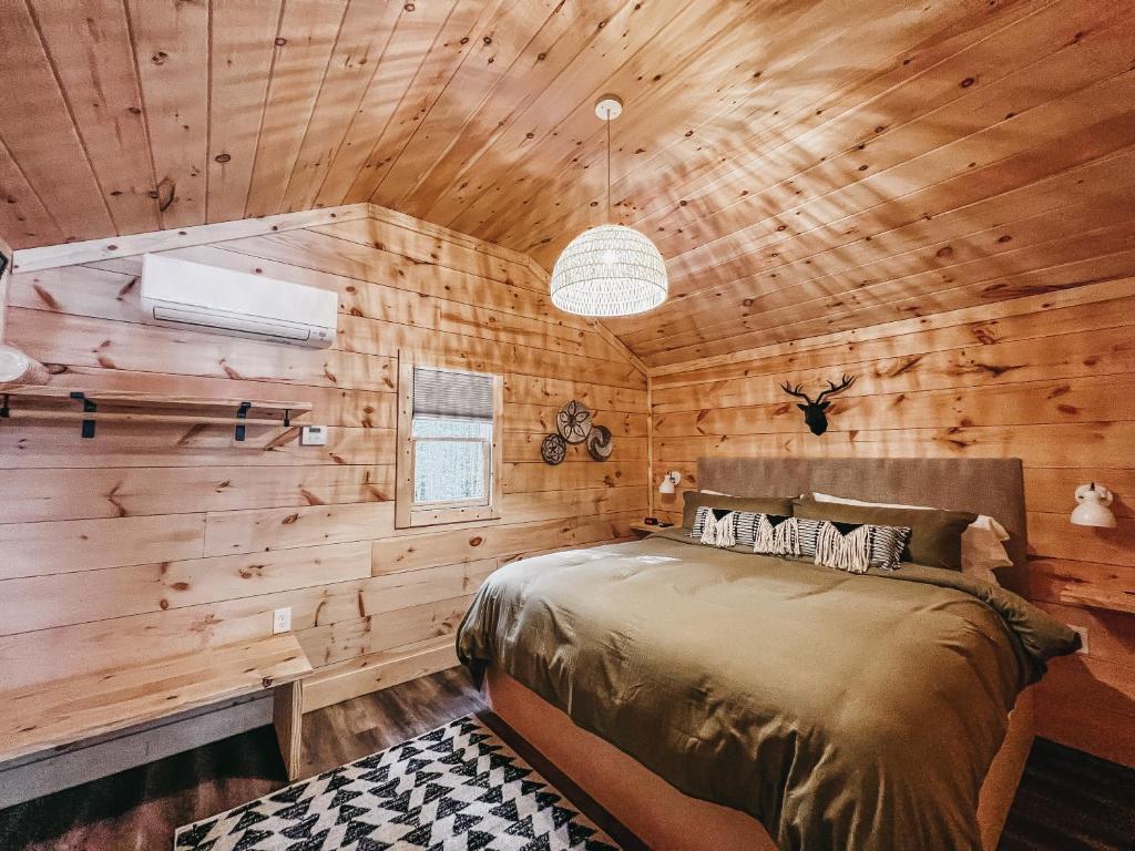 a bedroom with wooden walls and a bed in a room at Cabin #10 One Bedroom W Kitchenette in Hartwell