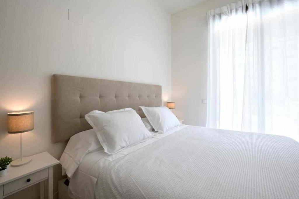 un letto bianco con cuscini bianchi e una finestra di Mike House Alójate en el corazón de Zaragoza a Saragozza