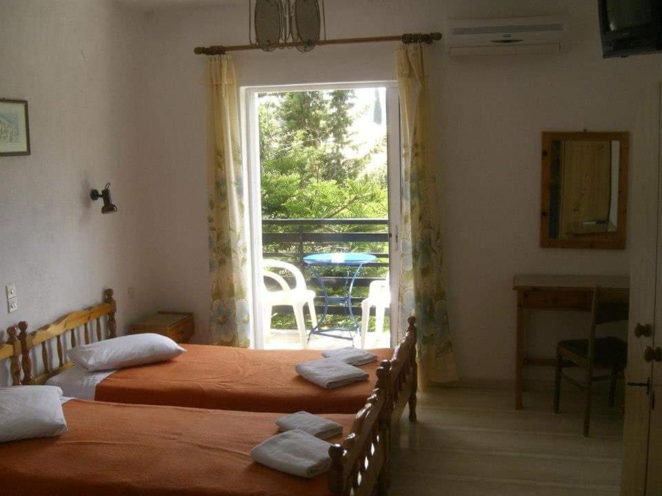 a bedroom with two beds and a door to a balcony at La Cite Family Hotel & Apartments in Moraitika