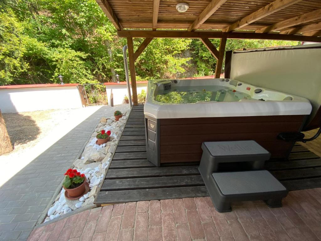 a hot tub on a patio with a wooden roof at HUTA-TÚRA 42 Vendégház in Háromhuta