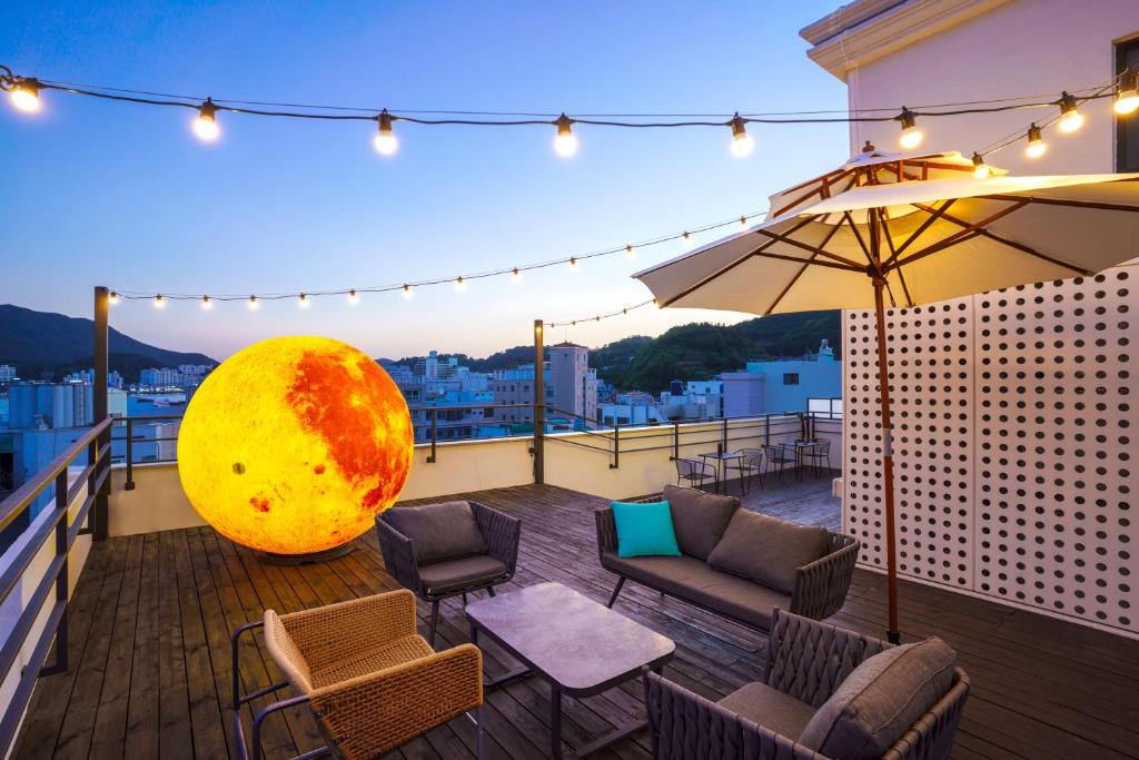 eine Terrasse mit Stühlen und einem Sonnenschirm auf dem Balkon in der Unterkunft Hotel Pico in Tongyeong