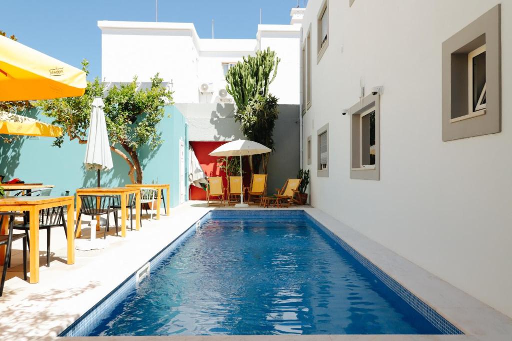 a swimming pool with tables and chairs next to a building at PTM DownTown Hostel&Suites in Portimão
