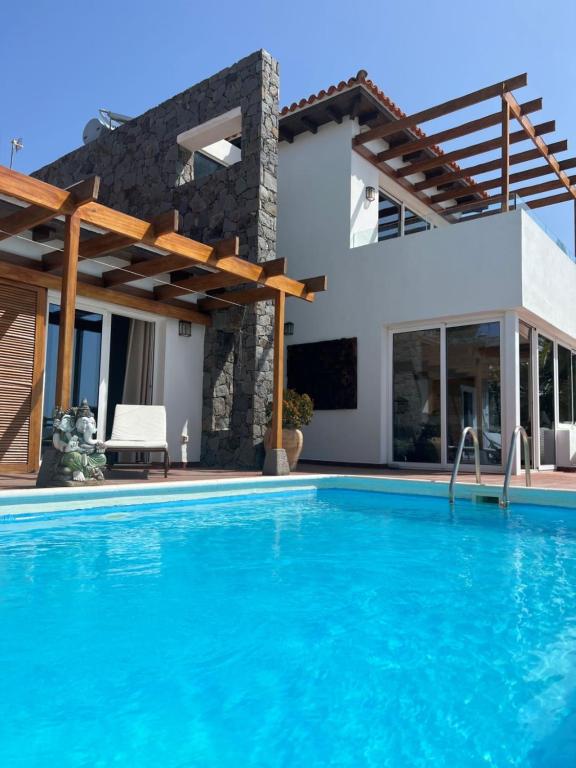 a villa with a swimming pool in front of a house at Villa Parque Mirador in Playa de Santiago
