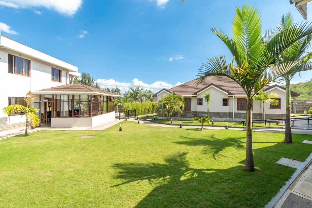 a yard with palm trees in front of a house at Rock Hyrax Hotel in Nakuru