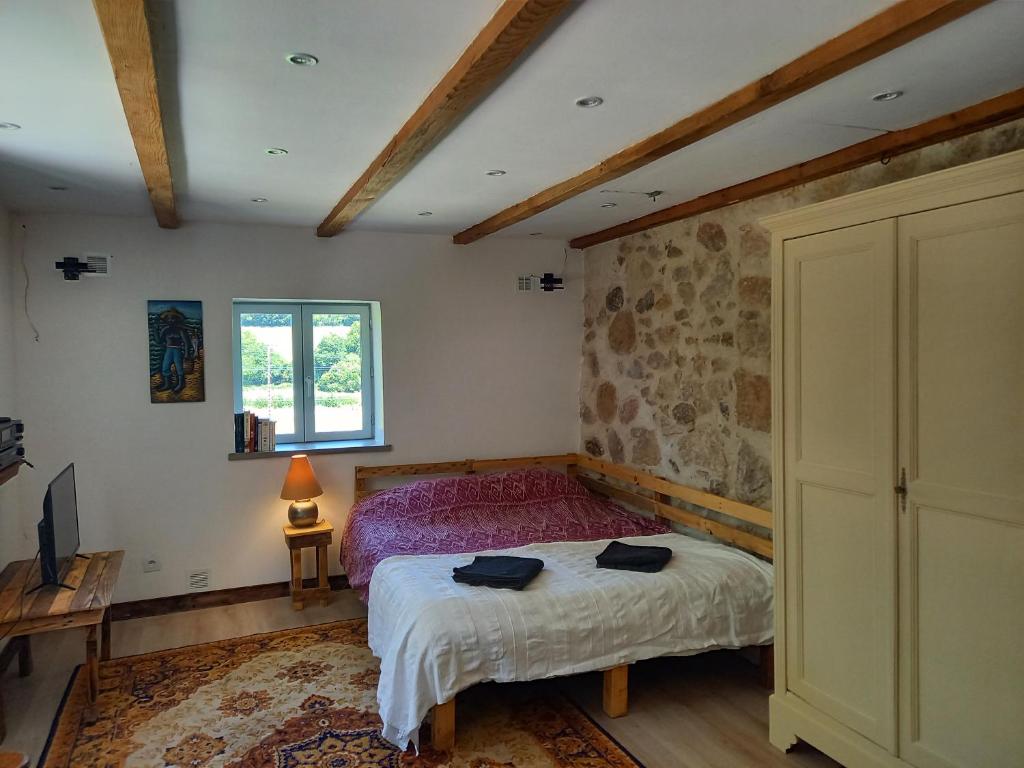 a bedroom with a bed and a stone wall at Le Studio du Crot Noir in Cussy-en-Morvan