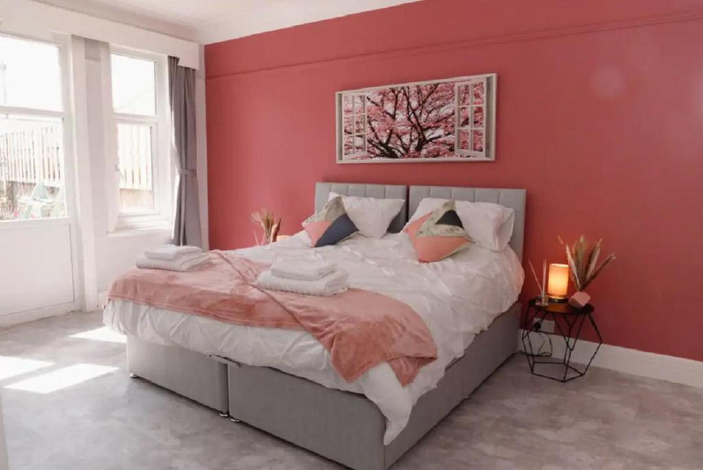 a bedroom with a large bed with a red wall at Lovely, Cosy Beachside Cottage 1 - Perfect Location in Llandudno