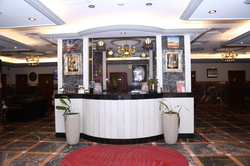un bar en el vestíbulo de un hotel con dos jarrones blancos en Jarzez Hotel Apartments Al Hail en Seeb