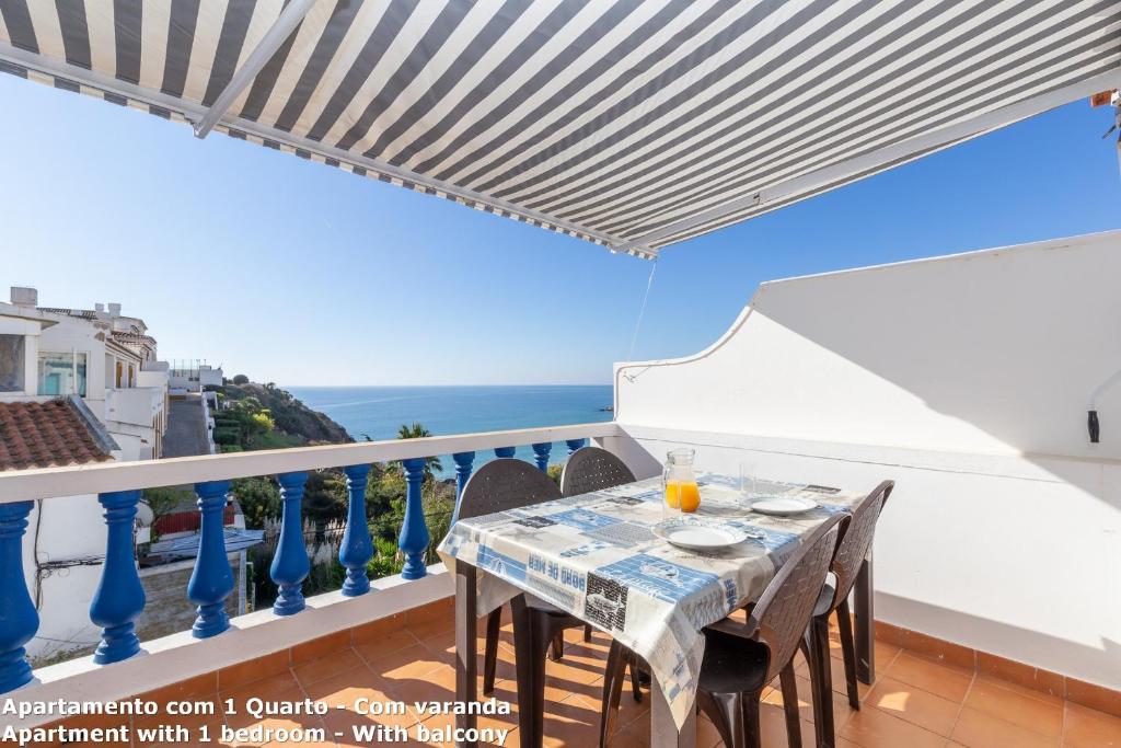 a dining table on a balcony with a view of the ocean at Akisol Lagos Beach in Burgau