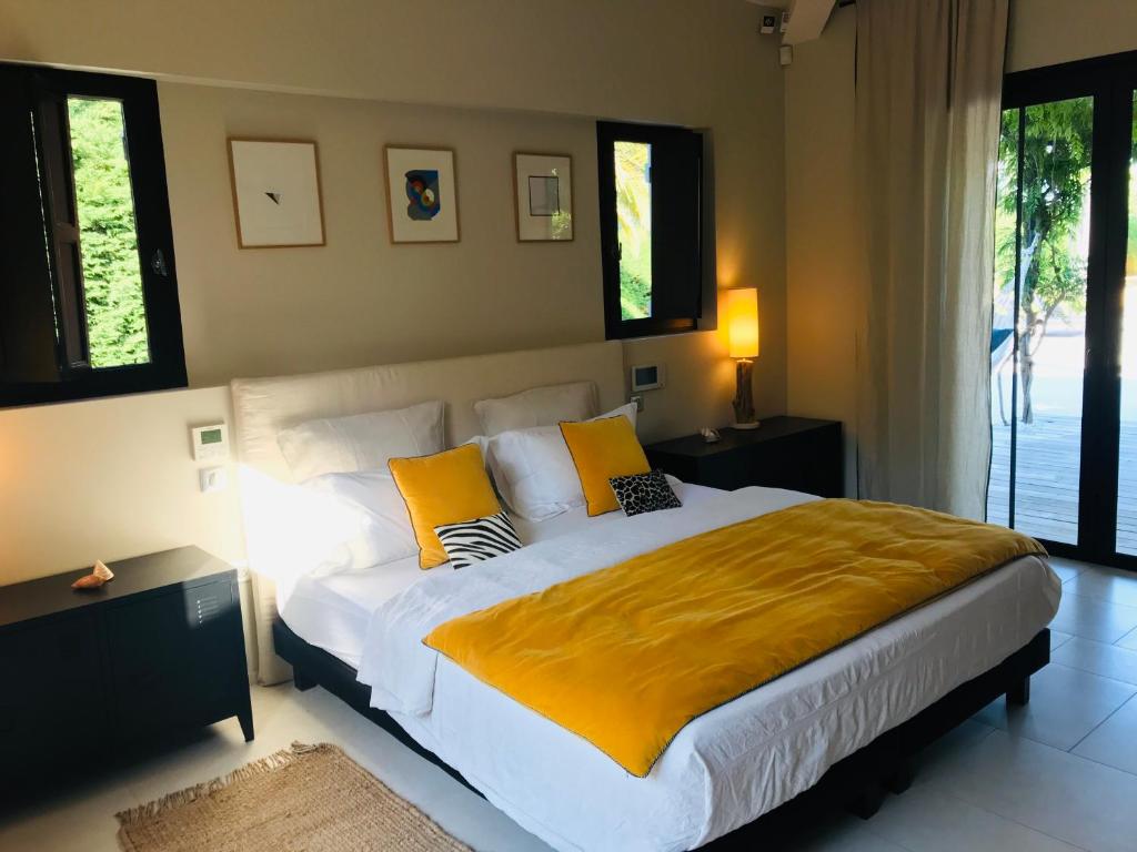 sypialnia z dużym łóżkiem z żółtymi kocami i poduszkami w obiekcie Villa Beausoleil w mieście Ramatuelle