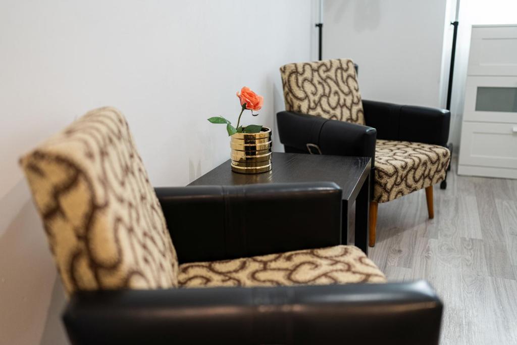 een woonkamer met 2 stoelen en een tafel met een bloem erop bij King Seventeen Homes in Boedapest