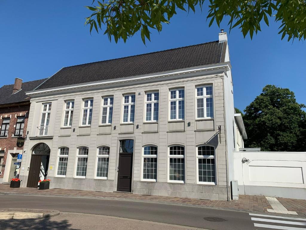 a large white building with white windows on a street at Sleutelhuys in Tielt