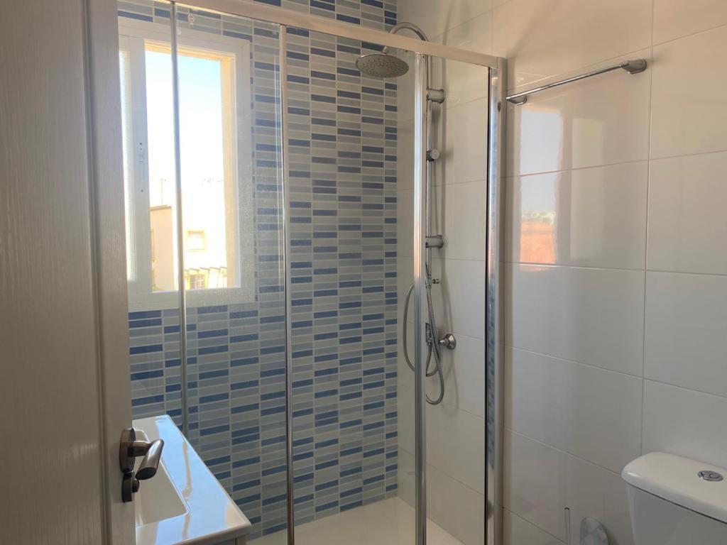 baño con ducha y aseo y ventana en Apartamento Vista Al Mar Calle Ciruela, en El Puerto de Santa María