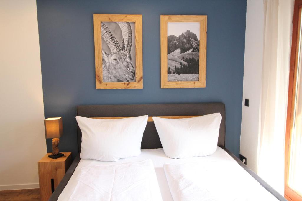 um quarto com uma cama com três fotografias na parede em Ferienwohnung im Zentrum von Oberstaufen em Oberstaufen