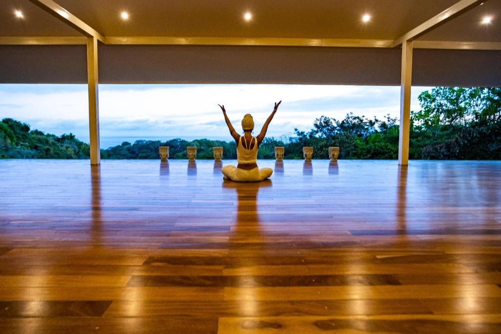 a woman is sitting in a yoga pose in a room at Aves Hotel Montezuma in Montezuma