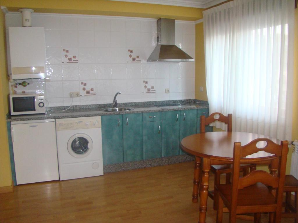 cocina con mesa, fregadero y lavadora en Apartamentos Peña Mar en Castropol