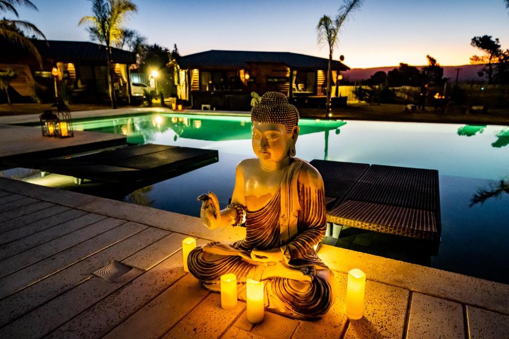 Una statua di una donna meditatrice con le candele accanto a una piscina di OMM Suites Resort, Villa General Belgrano a Villa General Belgrano