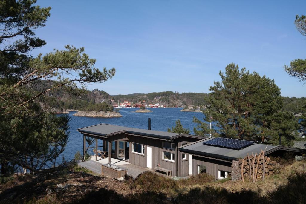 a house with solar panels on the side of a lake at Keybutler Holiday Cabin Nettholmen in Kristiansand