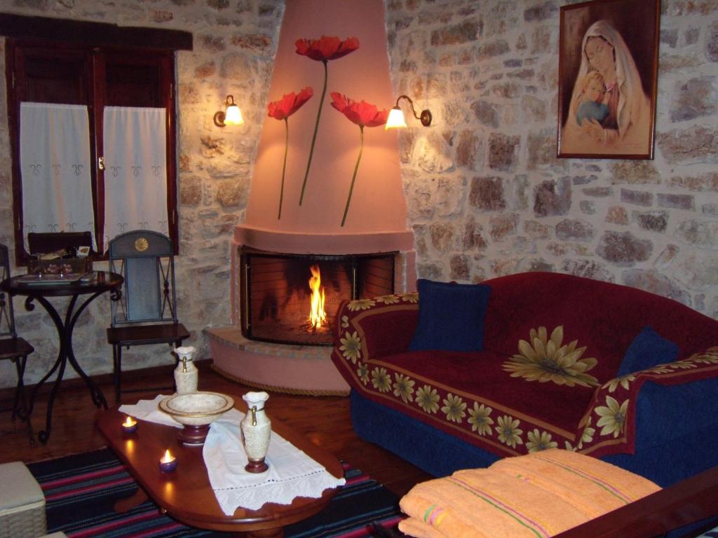 un soggiorno con camino, divano rosso e camino di Arhontiko Kordopati Traditional Guesthouse a Daras