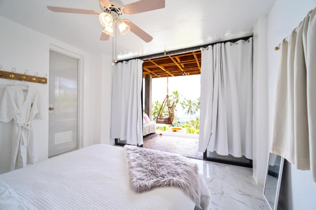 een slaapkamer met een bed en een plafondventilator bij Bintana sa Paraiso Binunsaran in Mambajao