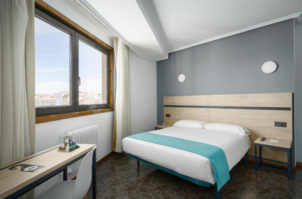 a hotel room with a bed and a window at Hotel Alda Pasaje in Gijón